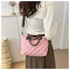 Detail of pink quilted tote bag showing vintage pattern strap and textured fabric