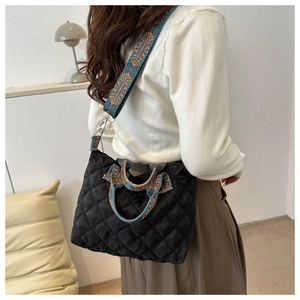 Detail of black quilted crossbody bag with vintage ethnic patterned strap and handle