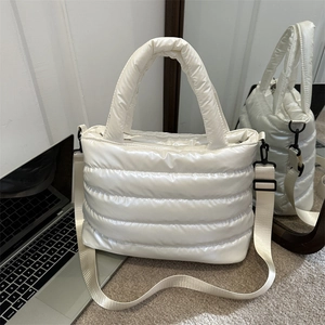 Sac bandoulière rembourré blanc avec large sangle présenté dans un bureau à domicile moderne