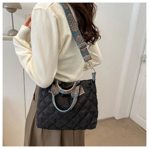 Close-up of black quilted tote bag with unique ethnic pattern wide shoulder strap