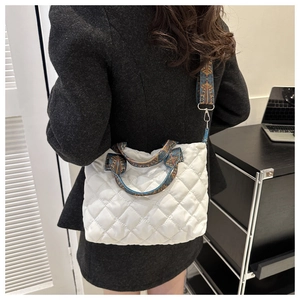 Close-up of quilted tote bag featuring retro blue and gold pattern straps on black coat