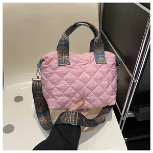 Close-up of pink quilted tote bag showing geometric patterned strap and puffer texture