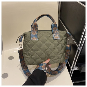 Close-up of olive green quilted handbag with geometric pattern woven shoulder straps