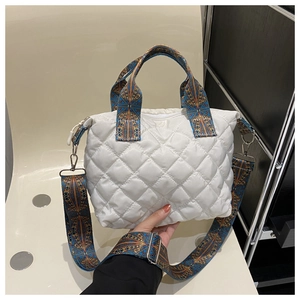 Close-up of quilted nylon tote bag with wide ethnic pattern strap and metal buckle detail