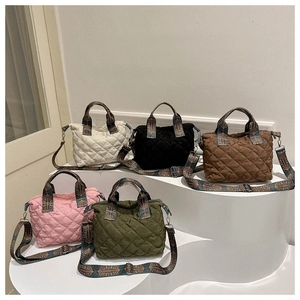 Quilted tote bags in multiple colors with patterned straps shown on display stands