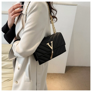 Détail d'un sac bandoulière noir matelassé avec logo V doré et pampille métallique