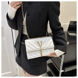 Détail du sac matelassé blanc avec logo V doré, bandoulière chaîne et pompon élégant