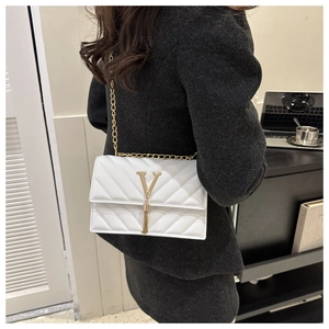 Détail du sac bandoulière blanc matelassé avec logo V doré et pompon sur le mannequin