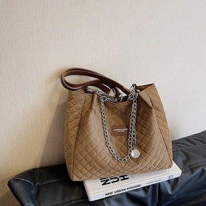 Gros plan sur le sac cabas matelassé marron avec chaînes argentées et étiquette en cuir