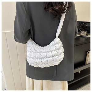 Close-up of white puffer hobo bag showing quilted texture and golden zipper detail