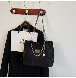 Détail du sac cabas matelassé noir avec chaîne argentée et bandoulière en cuir brun