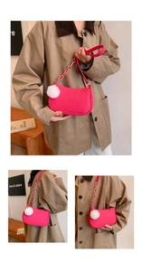 Detail of fuchsia crossbody bag featuring faux crocodile texture and white pompom charm