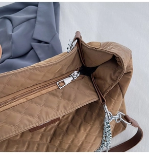 Détail du sac cabas matelassé marron avec fermeture éclair lisse et chaîne argentée