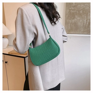 Green faux crocodile texture crescent underarm bag with gold hardware on grey blazer