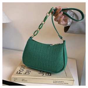 Detail of green faux leather crossbody bag with crocodile texture and resin chain