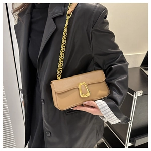 Details der hellbraunen Umhängetasche mit goldener Hufeisenschnalle auf Lederblazer