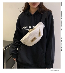 Dettaglio della borsa pettorale in nylon bianco sporco con patch FASHION e tracolla nera