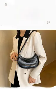Detailed view of black patent leather hobo bag with glossy textured finish and sleek shoulder strap
