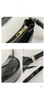 Close-up of shiny black underarm bag featuring golden metal hardware and smooth wax leather