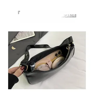 Interior view of black glossy underarm bag showing large capacity for makeup and phone