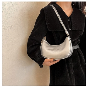 Silver metallic crescent underarm bag styled with a minimalist black dress on a model