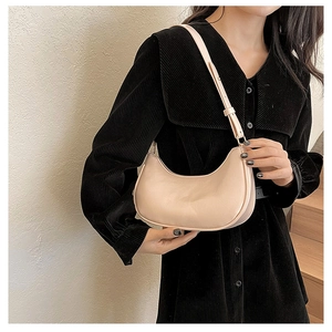 Chic beige half-moon shoulder bag styled on a black corduroy dress with a neutral background