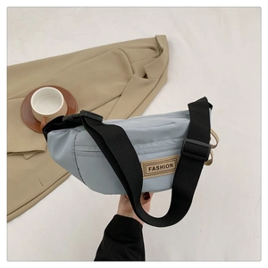 Dettaglio della borsa a tracolla in nylon azzurro con etichetta fashion e fibbia
