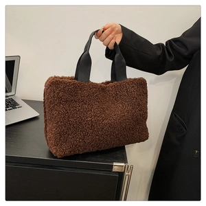 Nahaufnahme einer braunen Teddy-Plüschtasche mit schwarzem Gurt im modernen Büroumfeld