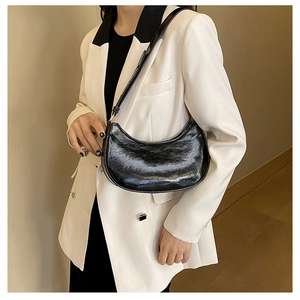 Glossy black pleated leather half-moon shoulder bag styled with a white blazer