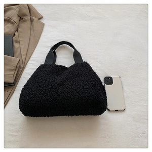 Draufsicht auf schwarze flauschige Fleece-Beuteltasche neben Smartphone als Größenvergleich