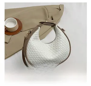 Gros plan sur le sac demi-lune tressé blanc avec bordure marron et bandoulière réglable