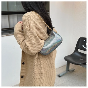 Iridescent silver underarm bag with gold chain strap shown on model over the shoulder