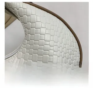 Gros plan sur la texture en cuir tressé blanc d'un sac demi-lune avec fermeture éclair métal