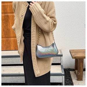 Chic iridescent silver crescent shoulder bag with golden chain strap on a model