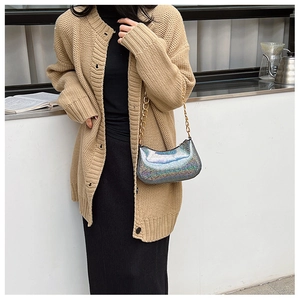 Detail of laser silver sequin chain bag paired with a khaki knit cardigan and black outfit