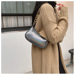 Borsa olografica argento con catena dorata indossata da una modella in cardigan beige