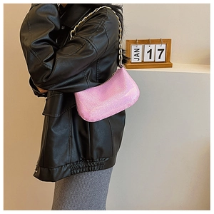 Dettaglio borsa sottobraccio glitter rosa con tracolla a catena dorata su modella