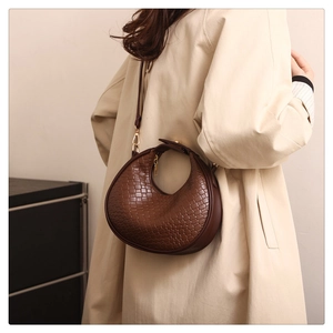 Close-up of brown woven crescent bag with gold hardware and synthetic leather texture