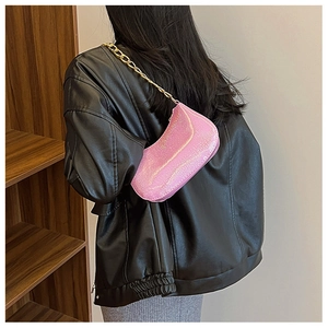 Dettaglio della borsa baguette con paillette rosa e tracolla a catena dorata su spalla