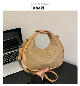 Détail de sac demi-lune tressé kaki avec fermeture éclair dorée et texture tissée
