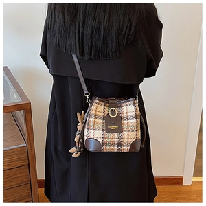 Detail of tweed bucket bag with brown faux leather trim and cute plush rabbit charm