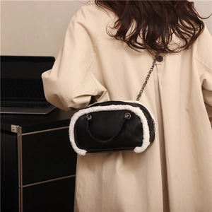 Winter faux fur trim black leather shoulder bag with chain strap on a beige coat
