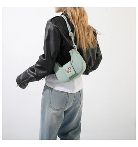 Detail of light green crescent bag with golden butterfly clasp and pebble leather texture