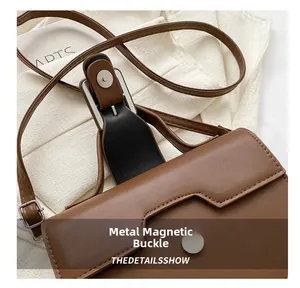 Detail of a brown leather shoulder bag featuring a silver magnetic hardware buckle