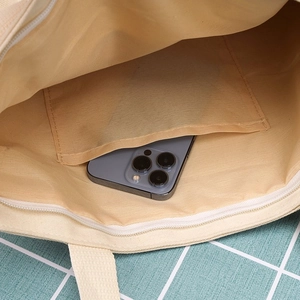 Dettaglio interno della borsa tote in tela beige con tasca a zip e fodera in tessuto