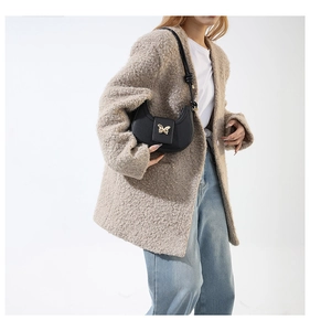 Detail of black pebbled leather half-moon bag with golden butterfly lock on lamb wool coat