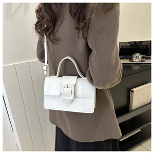 Side view of a glossy white leather shoulder bag with a stylish large square buckle decoration
