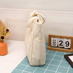Dettaglio della borsa tote in tela crema con tasca laterale e doppi manici robusti