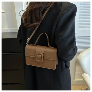 Brown retro PU leather shoulder bag with decorative buckle shown on a black coat