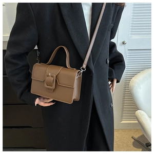 Detail of vintage brown leather handbag featuring top handle and adjustable shoulder strap